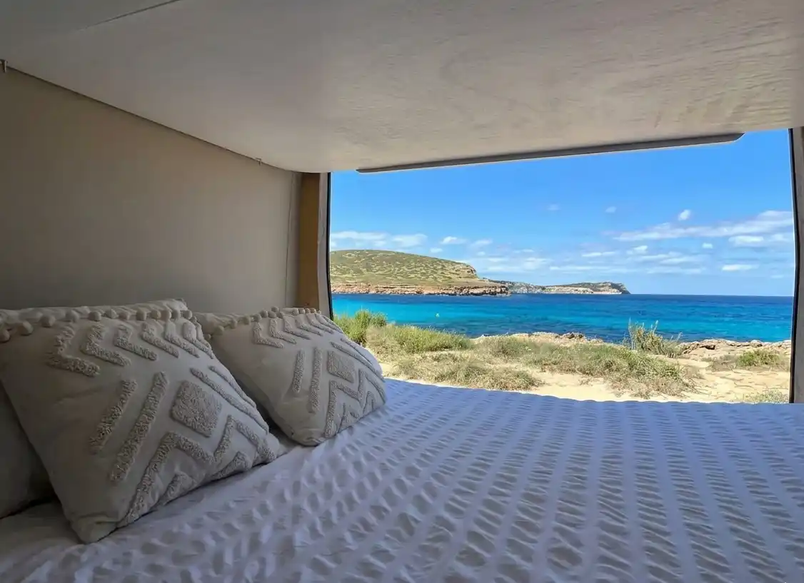 Cama de matrimonio confortable en furgoneta camper Hyundai H350 con vistas al mar.
