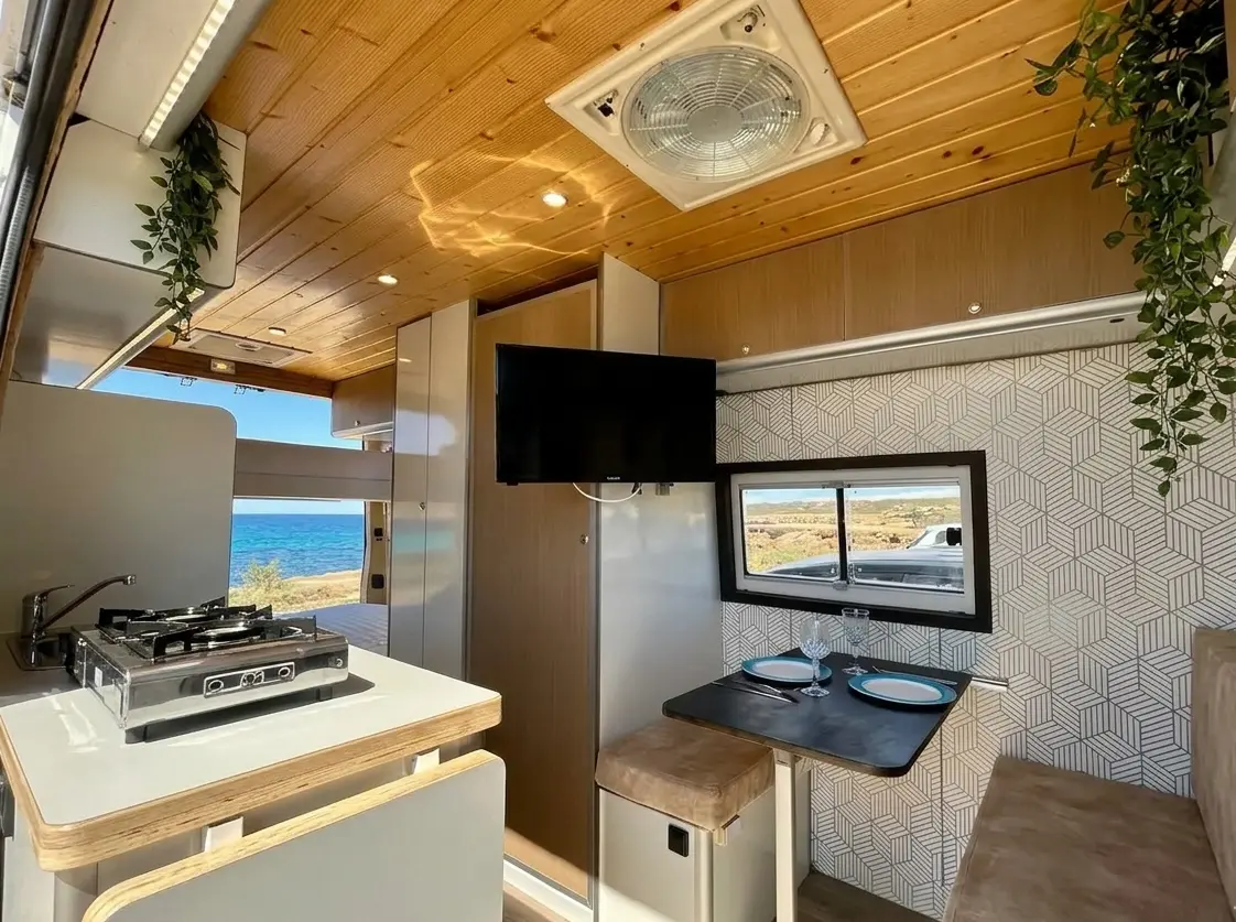 Interior equipado de la furgoneta camper Hyundai H350 La Diosa Tanit en Ibiza con cocina y mesa comedor